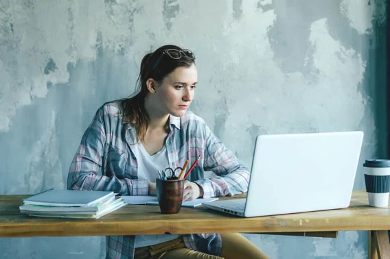Student sitting at table, looking at laptop